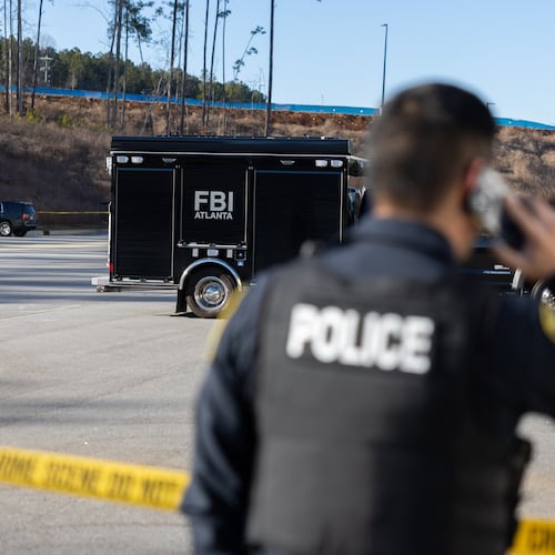 A police officer keeps guard in front of crime scene tape as the FBI conducts a raid on the Fulton County Election Hub and Operation Center in Union City on Wednesday, Jan. 28, 2026. (Arvin Temkar/AJC)