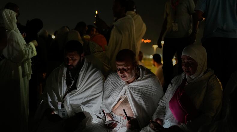 Muslim pilgrims read a copy of Islam's holy book Quran atop of the rocky hill known as the Mountain of Mercy, on the Plain of Arafat, during the annual Hajj pilgrimage near the holy city of Mecca, Saudi Arabia, Tuesday, May 26, 2026. (AP Photo/Altaf Qadri)