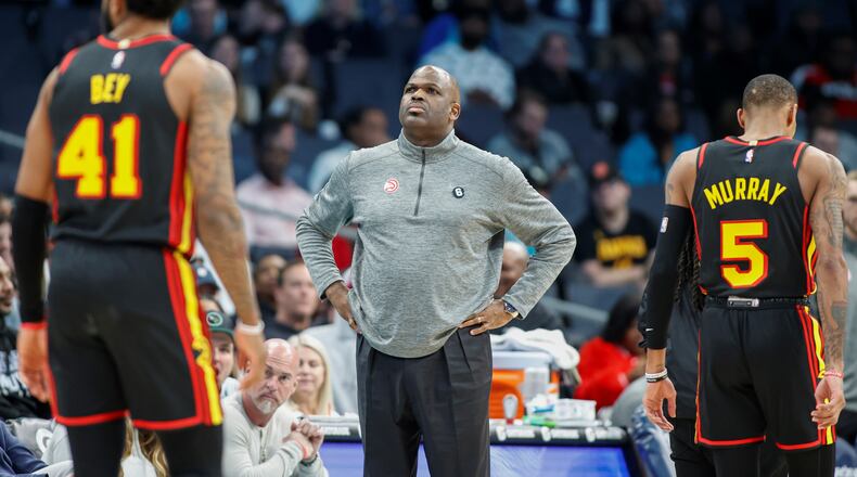 Hawks head coach Nate McMillan, center, stands on the court as forward Saddiq Bey (41) and guard Dejounte Murray (5) walk to the bench during a timeout during the second half of an NBA basketball game against the Charlotte Hornets in Charlotte, N.C., Monday, Feb. 13, 2023. (AP Photo/Nell Redmond)