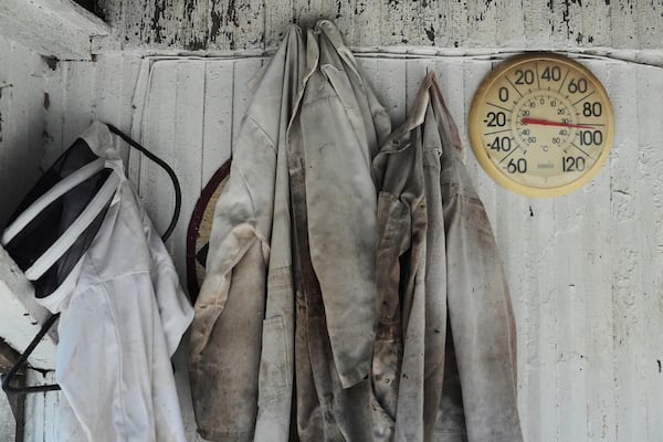 Beekeeping suits hang next to an outdoor thermometer Tuesday, June 24, 2025, at Honeyrun Farm in Williamsport, Ohio. (AP Photo/Joshua A. Bickel)