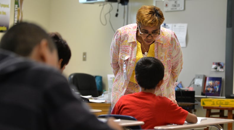 Gloria Watson helps an eighth-grade student at Tucker Middle School with a class assignment. Watson, a retired teacher, was substituting at the DeKalb County middle school when this picture was taken in 2015. District records indicate DeKalb’s school system doesn’t find a substitute for every time a teacher is absent. BRANT SANDERLIN/BSANDERLIN@AJC.COM