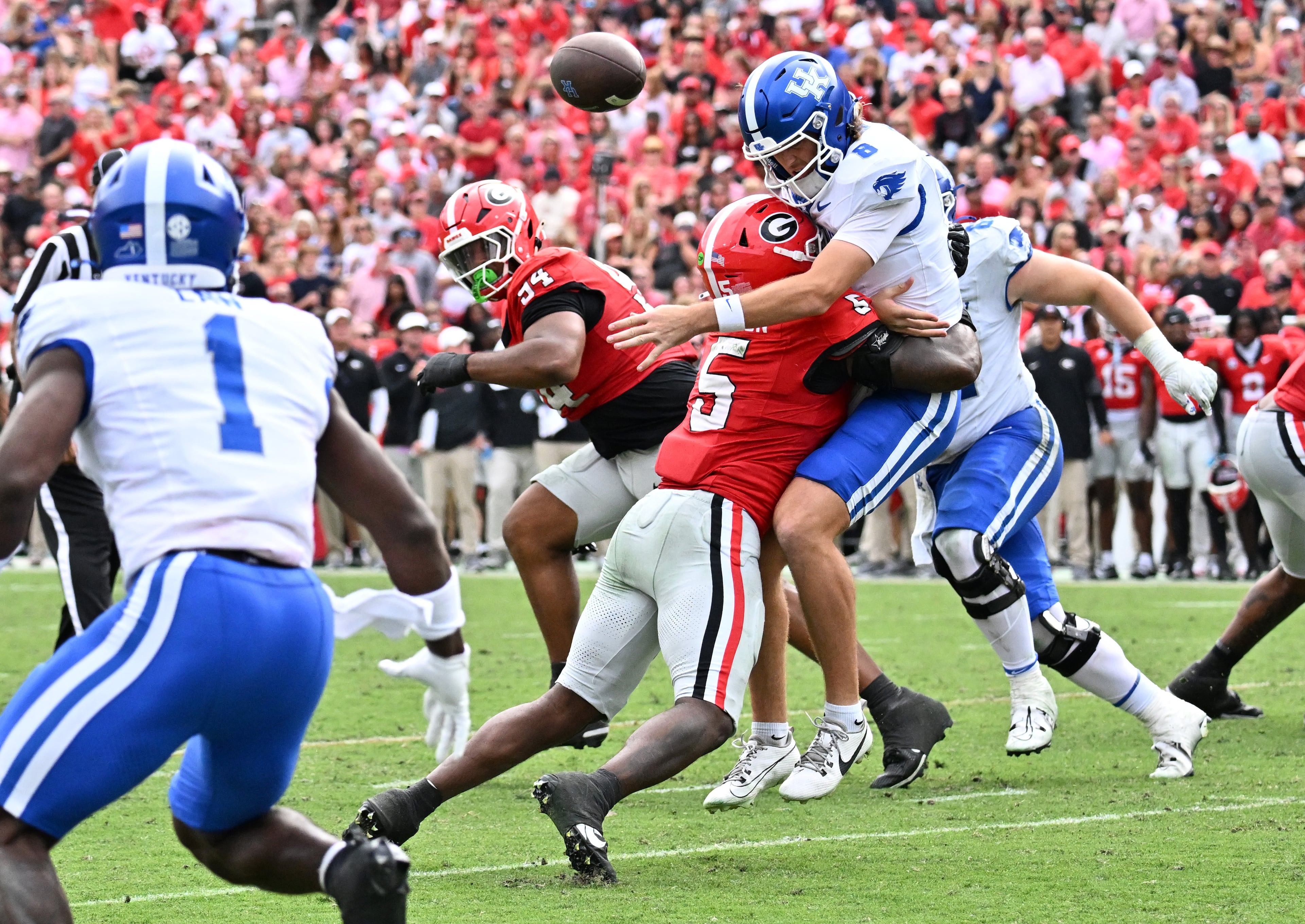Kentucky quarterback Cutter Boley (8) gets tackled by Georgia linebacker Raylen Wilson (5) as he tosses a ball to Kentucky linebacker Kameron Olds (1) during the second half in a NCAA college football game at Sanford Stadium, Saturday, October 4, 2025, in Athens. Georgia won 35 -14 over Kentucky. (Hyosub Shin / AJC)