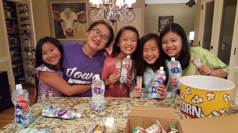 Emily Grace, Dora, Anna Claire, Eliana and Cate gather snacks before taking in a movie recently at the home of Amy Venn in Alpharetta. Venn and the other parents adopted the girls, all 11 now, in China on the same day. They gather every two years for a “family” reunion. CONTRIBUTED