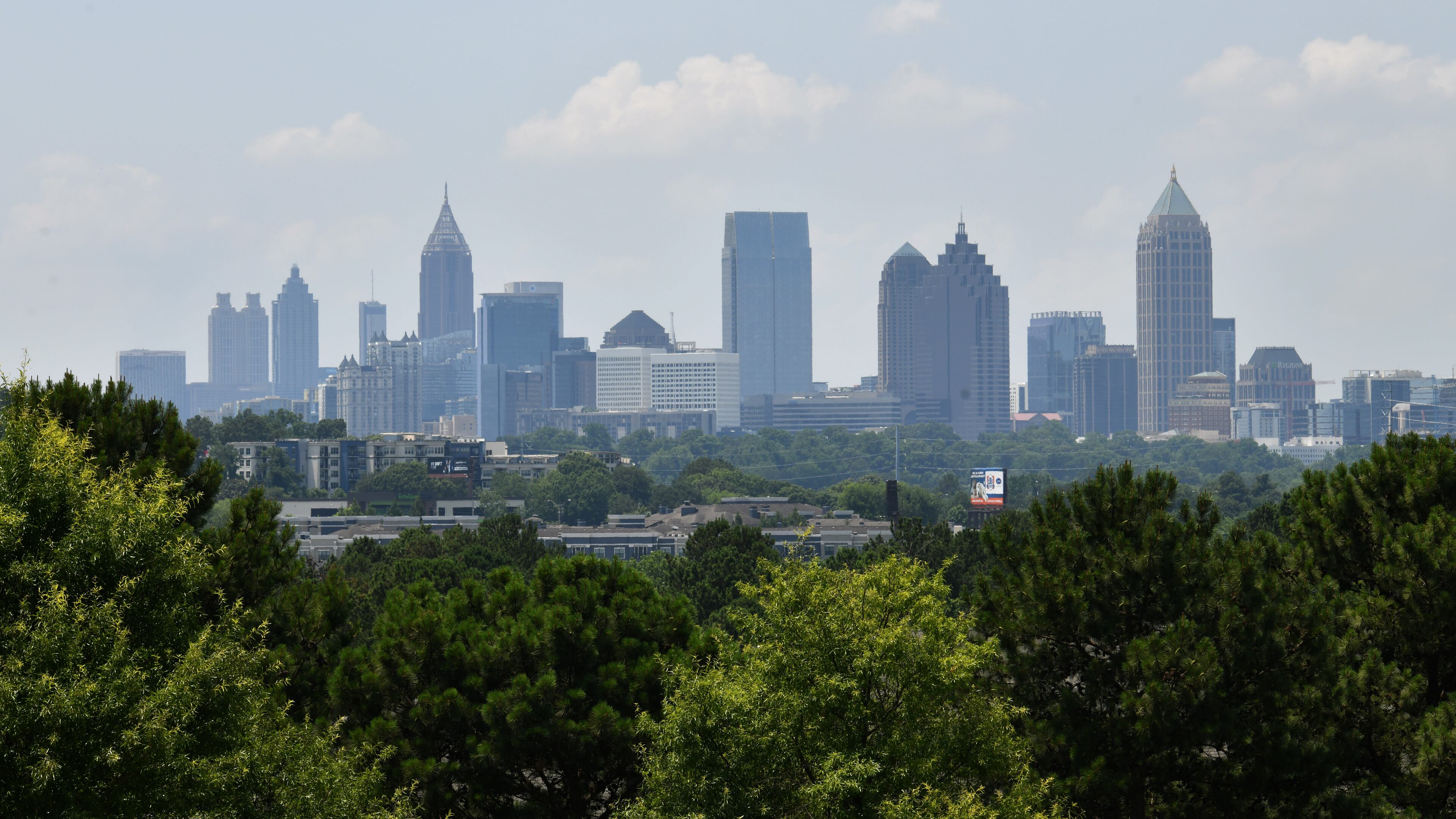 Trees are shown in the foreground of this photo of downtown Atlanta's skyline on Thursday, June 16, 2022. (Hyosub Shin / AJC)