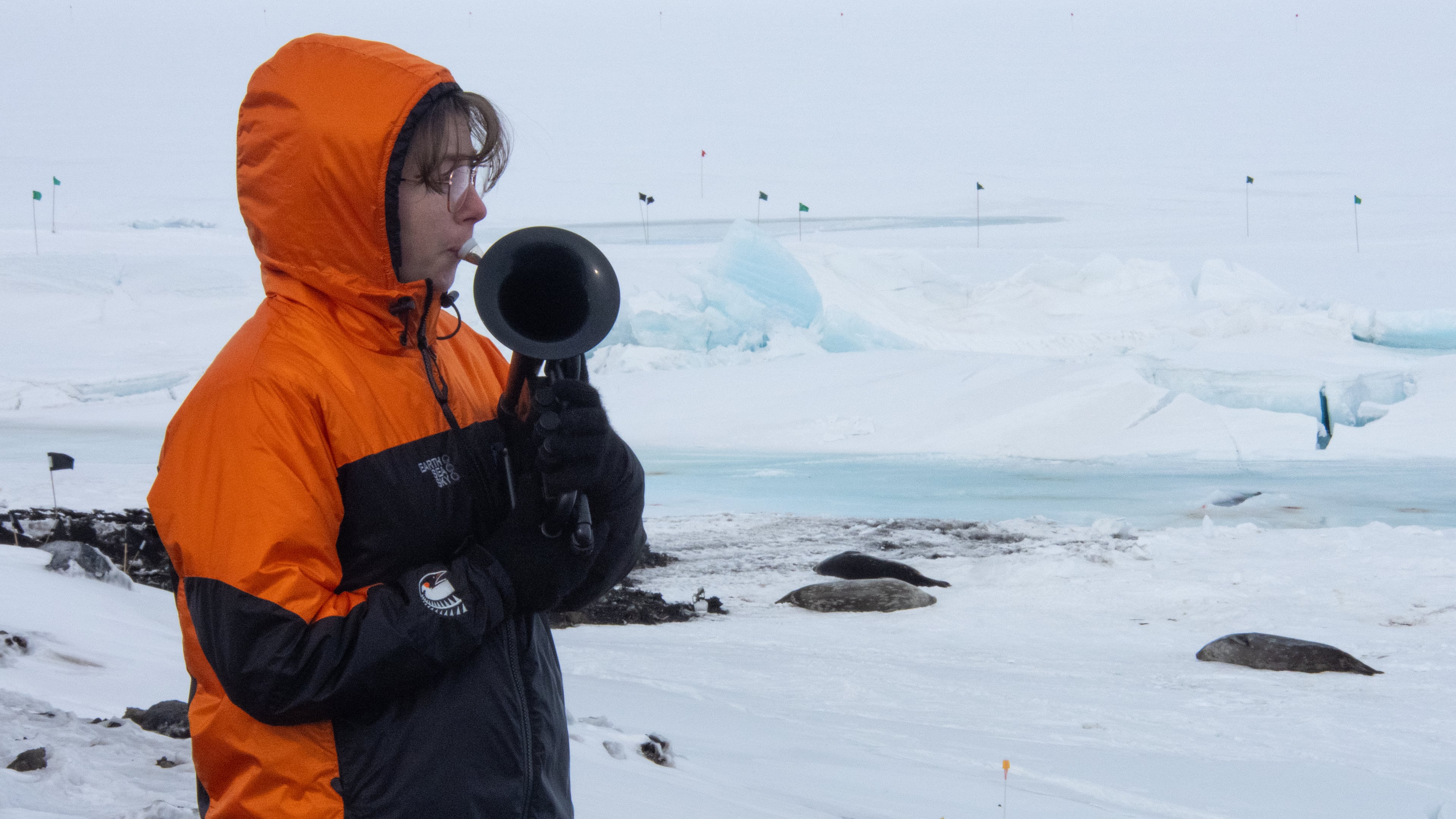 In this photo provided by Antarctica New Zealand, Natalie Paine plays a plastic French horn at Scott Base in Antarctica, on Nov. 16, 2025. (Anthony Powell/Antarctica New Zealand via AP)