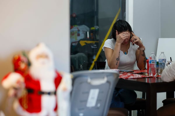 Ceudy Gutierrez reacts as she talks by phone to her husband, Omar Estribi, who has been held in an immigration detention center since early September. Ceudy is struggling to care for herself and her three young children following her husband’s arrest by ICE. (Miguel Martinez/AJC)
