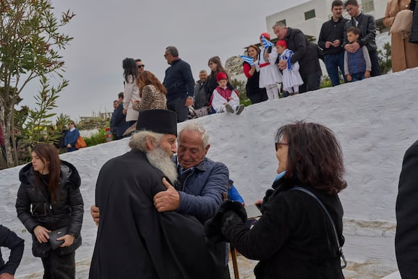 Orthodox Christian monk Father Spyridon is hugged by islanders as people gather to watch a parade for Greek Independence Day, which commemorates the start of the Greek War of Independence in 1821, in Amorgos island, Greece, on Tuesday, March 25, 2025. (AP Photo/Petros Giannakouris)
