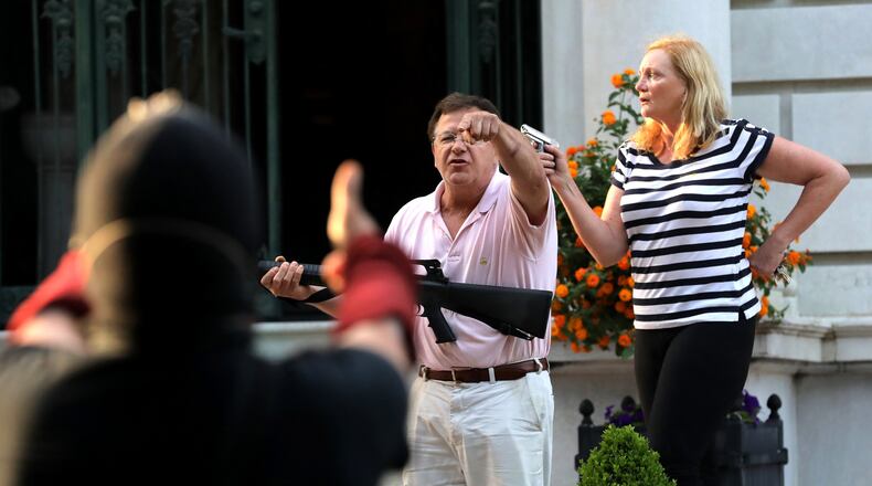 Armed homeowners Mark T. and Patricia N. McCloskey stand in front of their house along Portland Place as they confront protesters marching to St. Louis Mayor Lyda Krewson's house in June. The protesters called for Krewson's resignation for releasing the names and addresses of residents who suggested defunding the police department. (Laurie Skrivan/St. Louis Post-Dispatch/TNS)