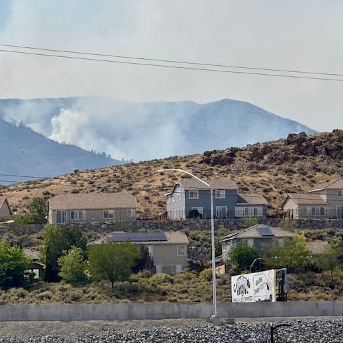 Smoke billows in the distance as a wildfire burns in Reno, Nev., Sunday, August 23, 2026. (AP Photo/Haven Daley)
