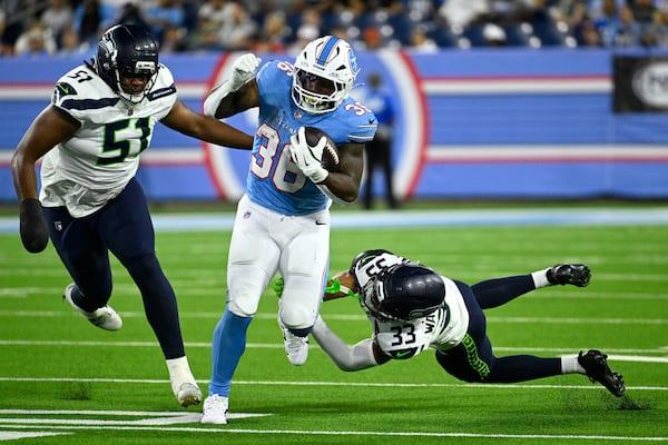 Titans running back Julius Chestnut (center) runs from then-Seahawks linebacker Jared Ivey (left) and cornerback Jordan Washington on Sunday, Aug. 23, 2026, in Nashville, Tenn. Seattle waived Ivey on Aug. 30, the final day of roster cuts. (John Amis/AP)