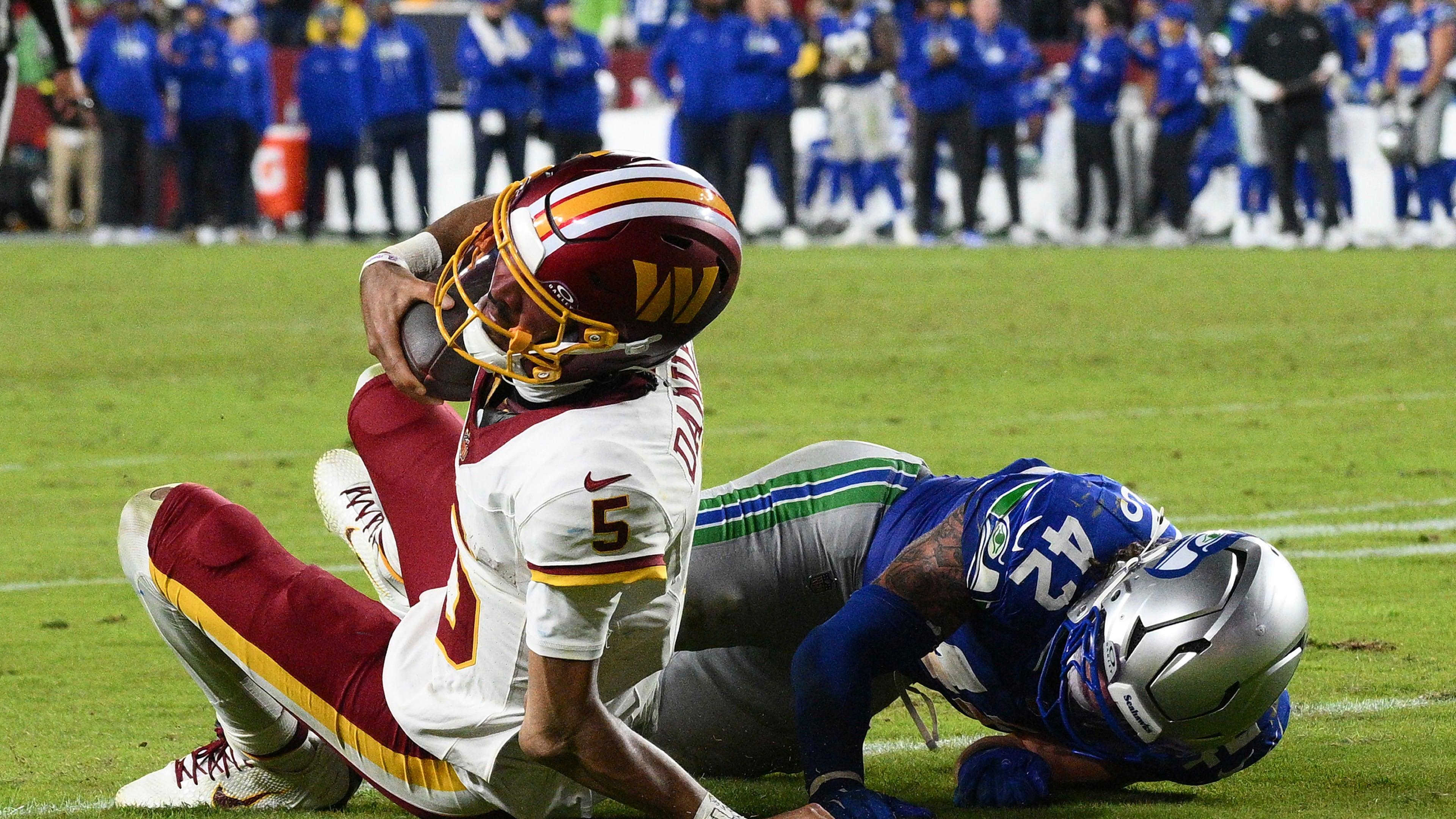 Washington Commanders quarterback Jayden Daniels (5) injures his arm as he is tackled by Seattle Seahawks linebacker Drake Thomas (42) during the second half of an NFL football game, Sunday, Nov. 2, 2025, in Landover, Md. (AP Photo/Nick Wass)