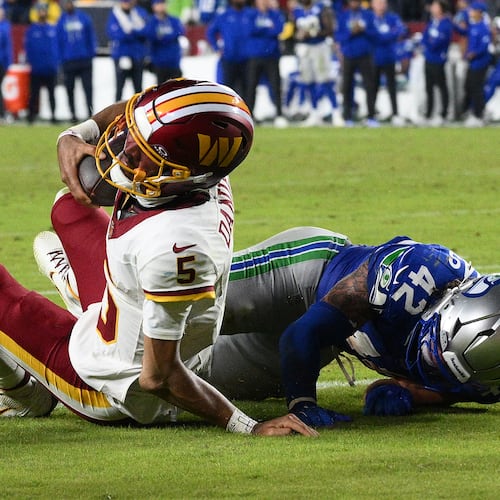 Washington Commanders quarterback Jayden Daniels (5) injures his arm as he is tackled by Seattle Seahawks linebacker Drake Thomas (42) during the second half of an NFL football game, Sunday, Nov. 2, 2025, in Landover, Md. (AP Photo/Nick Wass)