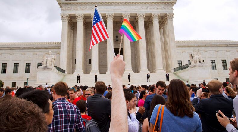 FILE - In this June 26, 2015 file photo, a man holds a U.S. and a rainbow flag outside the Supreme Court in Washington after the court legalized gay marriage nationwide. (AP Photo/Jacquelyn Martin)