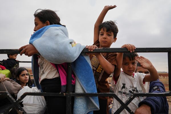 Syrian Bedouin families gesture as they ride in a convoy led by Red Crescent vehicles in Busra al-Harir, heading to Daraa after being evacuated from Sweida following more than a week of violent clashes, Monday, July 21, 2025. (AP Photo/Malek Khattab)