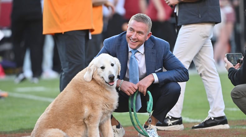 ESPN's Kirk Herbstreit and his dog Ben watch players warm up before the start of an NCAA college football game between Tennessee and Arkansas, Saturday, Oct. 5, 2024, in Fayetteville, Ark. (AP Photo/Michael Woods)