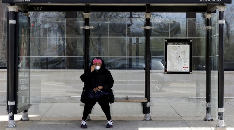 A pedestrian checks her mask as she waits for a bus during the COVID-19 pandemic in Chicago’s Logan Square, Friday, April 10, 2020. AP PHOTO / NAM Y. HUH