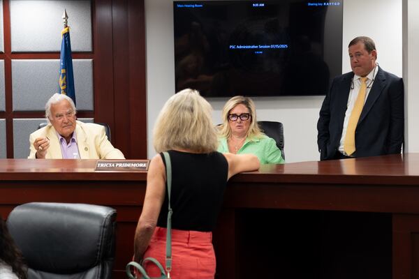 Commissioners Lauren “Bubba” McDonald (from left), Tricia Pridemore and Chairman Jason Shaw talk with Liz Coyle, executive director of Georgia Watch, during a break in a meeting of the Georgia Public Service Commission in July. (Ben Gray for the AJC)