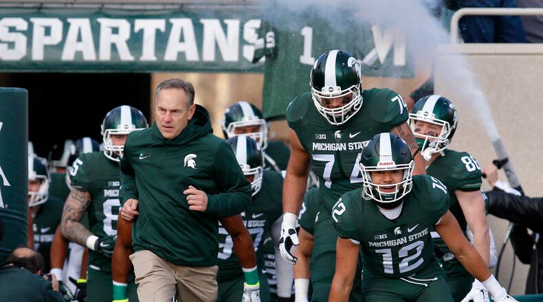 Michigan State coach Mark Dantonio, left, leads his team onto the field along with R.J. Shelton (12) and Jack Conklin (74) before an NCAA college football game against Penn State, Saturday, Nov. 28, 2015, in East Lansing, Mich. (AP Photo/Al Goldis)