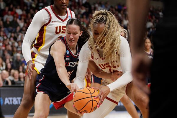 Southern California forward Kiki Iriafen, right, steals the ball from UConn guard Ashlynn Shade, front left, during the first half in the Elite Eight of the NCAA college basketball tournament, Monday, March 31, 2025, in Spokane, Wash. (AP Photo/Young Kwak)