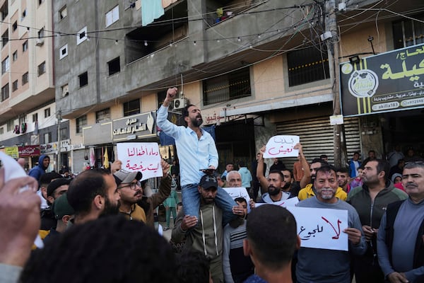 FILE - Palestinians hold signs at a protest against the war and Hamas in Deir al-Balah, Gaza Strip, Wednesday, March 26, 2025, in a rare show of public anger against the militant group that rules the territory. (AP Photo/Abdel Kareem Hana, File)