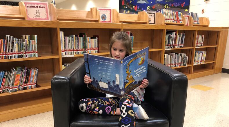 First-grader Lillian Boggs dives into a book by Sherri Rinker, an author who recently paid a virtual visit to Indian Knoll Elementary in Canton.