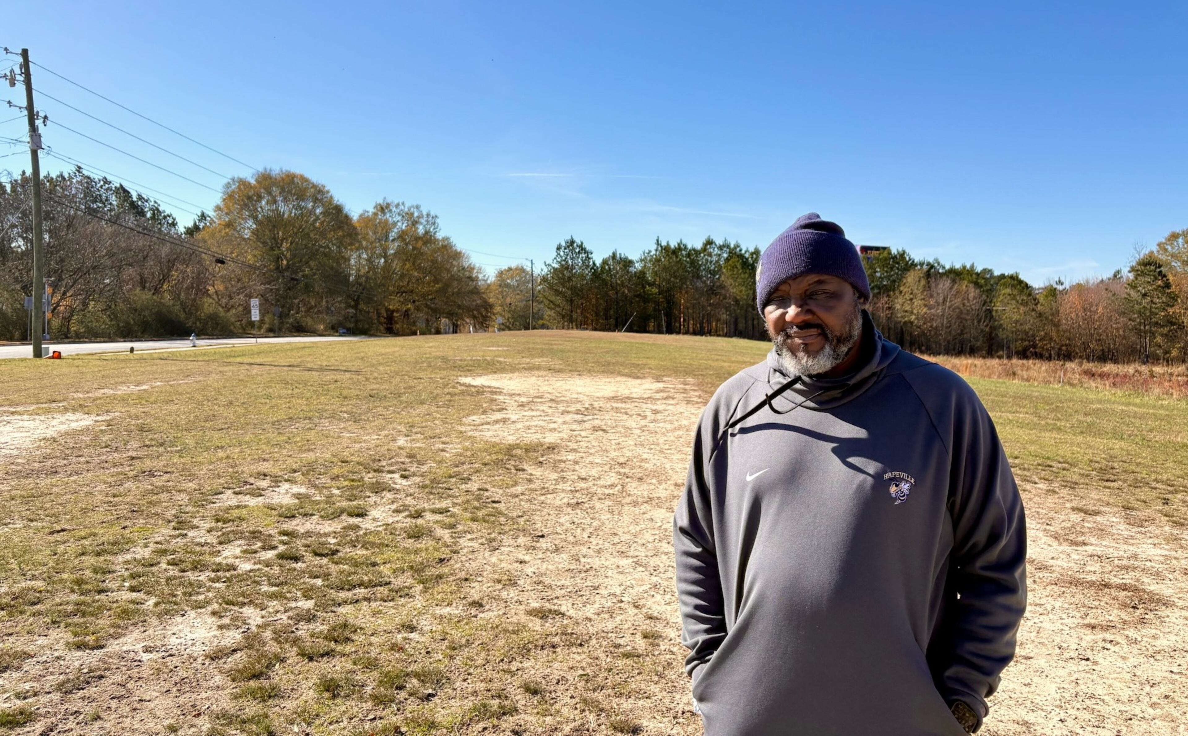Hapeville Charter coach Winston Gordon poses on his team's practice field adjoining the school Dec. 14, 2025. Gordon has been the football coach and athletic director since the school's opening in 2009. The field is bordered by Buffington Road in South Fulton. "People were constantly driving by honking," recalled Hapeville alumnus Best Uchehara. (Ken Sugiura/AJC)