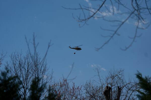 A helicopter does a water drop on the Black Cove Fire Wednesday, March 26, 2025, in Saluda, N.C.. (AP Photo/Allison Joyce)