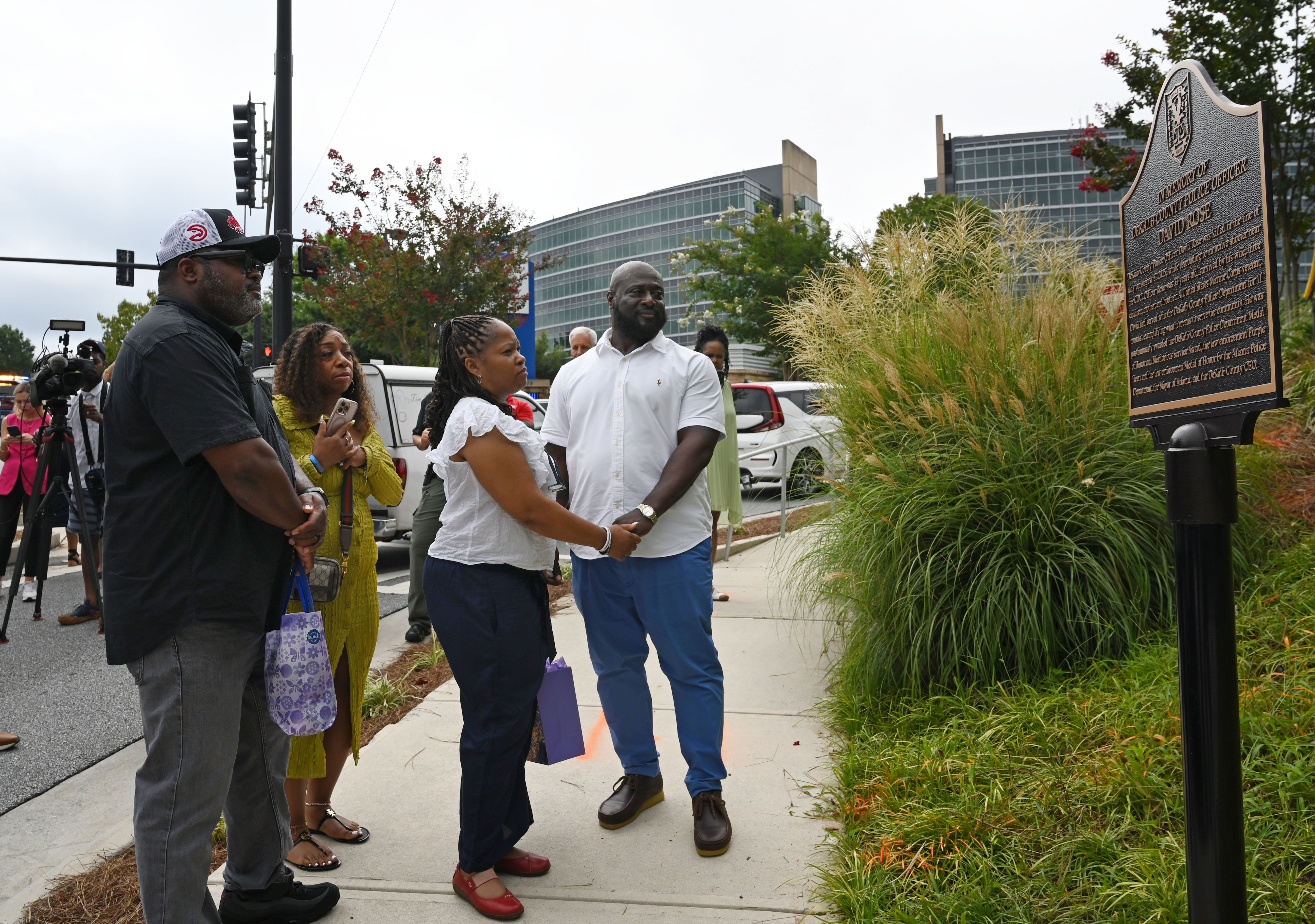 Family members visit a memorial plaque installed in honor of DeKalb County Police Officer David Rose outside the Centers for Disease Control and Prevention in Atlanta on Friday, Aug. 7, 2026. U.S. Secretary of Health and Human Services Secretary Robert F. Kennedy Jr. visited the CDC Friday to mark the one-year anniversary of the shooting that killed Rose. (Hyosub Shin/AJC)