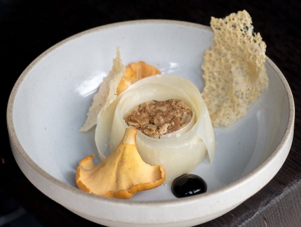 A close-up shot of an artfully arranged shallow bowl offering small amounts of cheese, date sauce and a mushroom or two.