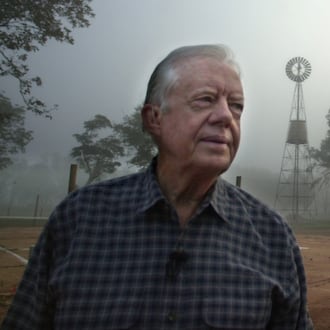 Former President Jimmy Carter looks over the site of his boyhood home and farm as a bank of fog lifts at day break near Plains, Ga., on Monday, Oct. 30, 2000. In the background is the family store and a windmill Carter's father erected in 1935 that supplied running water for the family for the first time. (Curtis Compton/AJC)