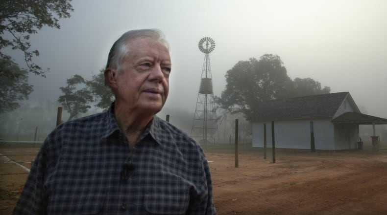 Former President Jimmy Carter looks over the site of his boyhood home and farm as a bank of fog lifts at day break near Plains, Ga., on Monday, Oct. 30, 2000. In the background is the family store and a windmill Carter's father erected in 1935 that supplied running water for the family for the first time. (Curtis Compton/AJC)