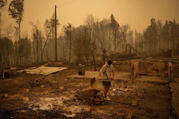 FILE - Yeremy Escanilla works on cleaning the debris of the remains of his house, destroyed by wildfires in Santa Juana, Chile, Feb. 5, 2023. (AP Photo/Matias Delacroix, File)