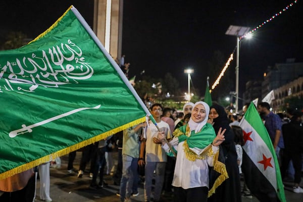 A girl holds a Saudi flag in celebration after U.S. President Donald Trump announced plans during his visit to Saudi Arabia to ease sanctions on Syria and normalize relations with its new government, in Homs, Syria, late Tuesday, May 13, 2025.(AP Photo/Omar Albam)