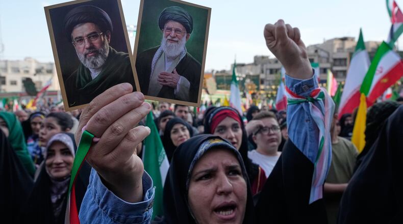 FILE - A woman holds up pictures of the Iranian Supreme Leader Ayatollah Mojtaba Khamenei, left, and his father, the slain Ayatollah Ali Khamenei, during a state-organized rally in Tehran, Iran, April 29, 2026. (AP Photo/Vahid Salemi, File)