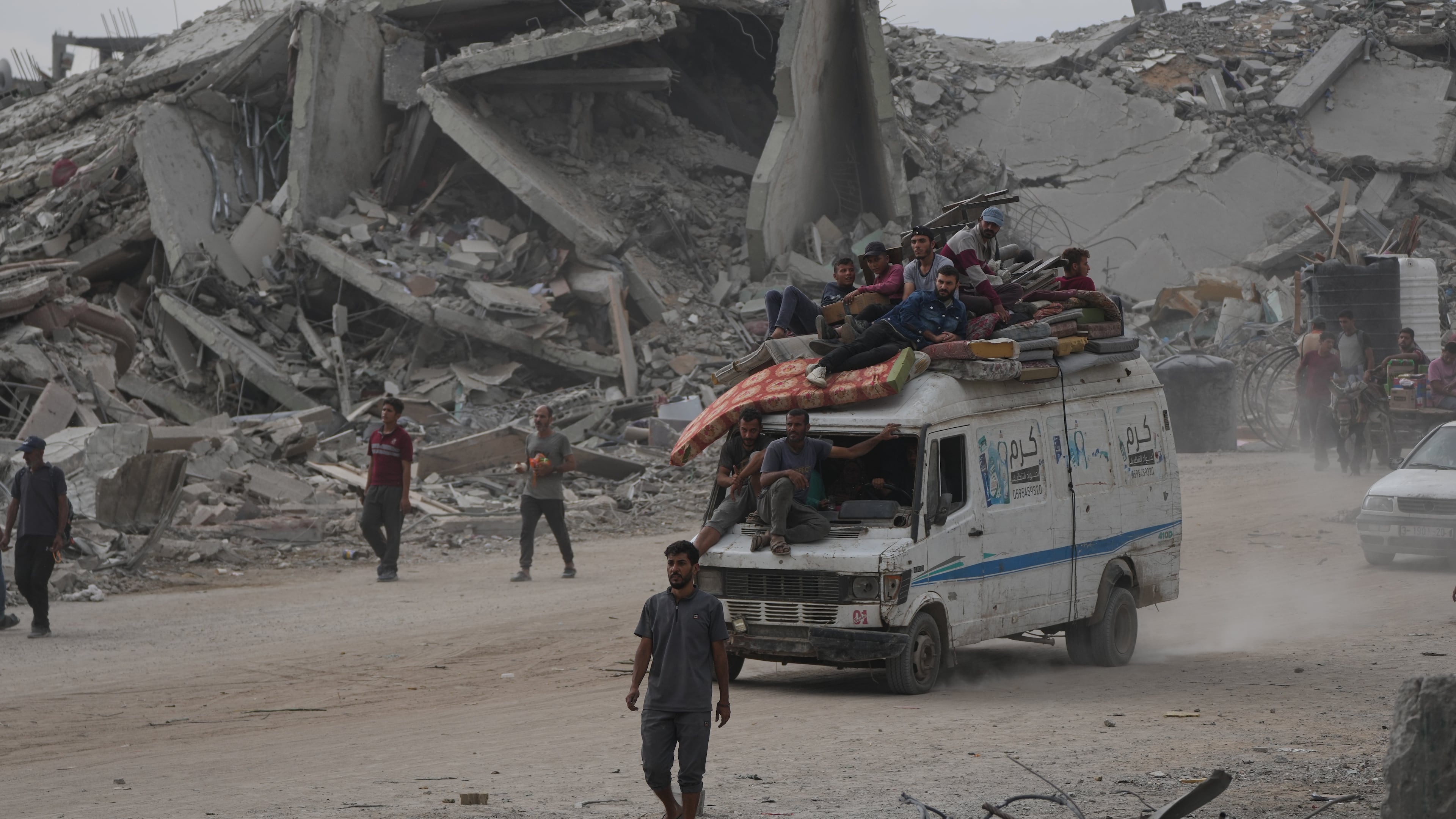 Displaced Palestinians ride on a van loaded with their belongings amid rubble in Gaza City, Sunday, Oct. 12, 2025, after Israel and Hamas agreed to a pause in their war and the release of the remaining hostages. (AP Photo/Abdel Kareem Hana)