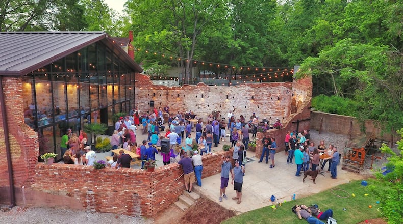 Taylor Lamm (foreground, left) and Nathan McGarity, co-owners of Oconee Brewing Company in Greensboro, raise their pint glasses to toast the grand opening of the brewery on May 6. Contributed by Clayviation