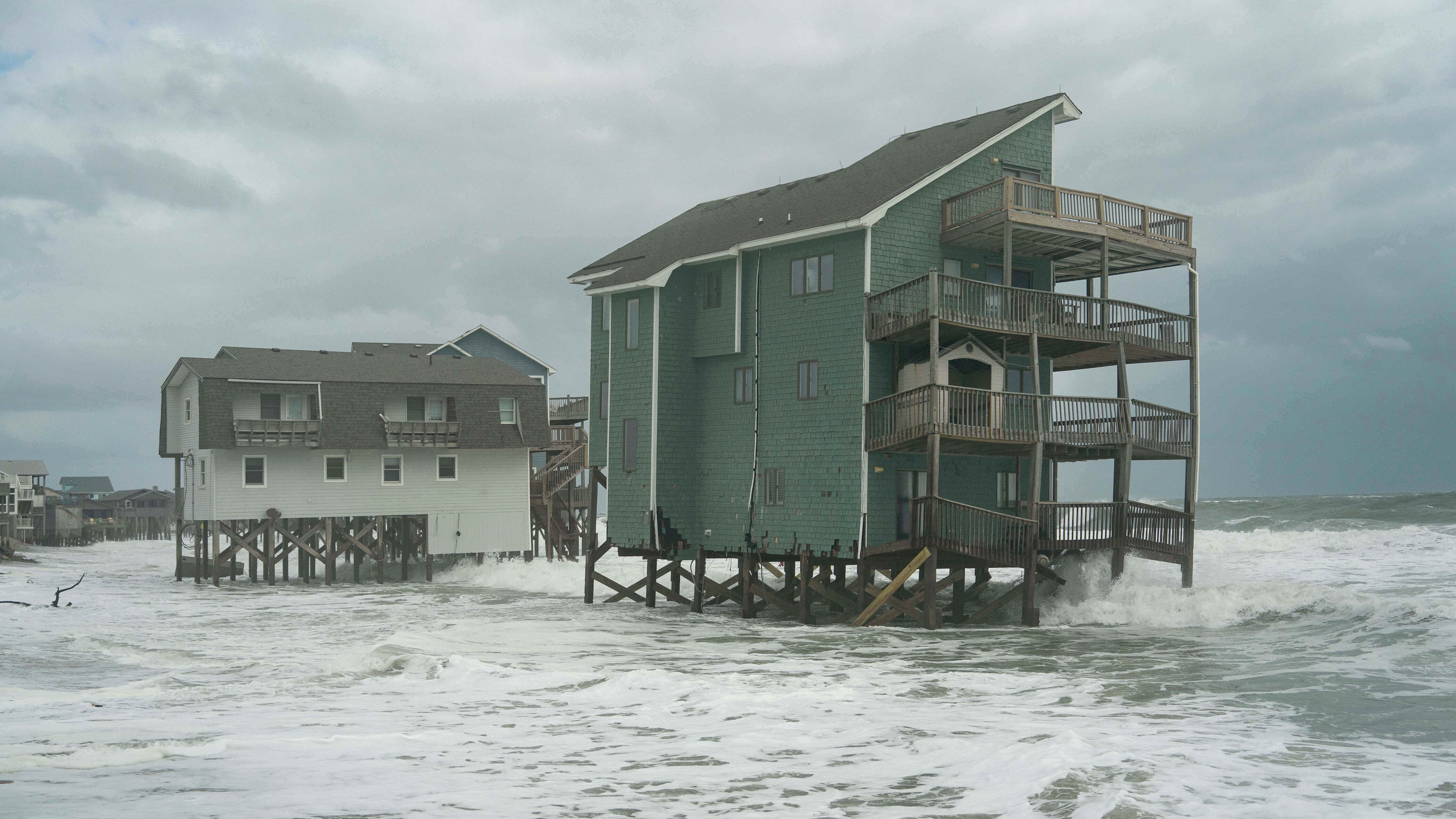 Homes at risk of falling into the ocean are visible as a storm approaches Friday, Oct. 10, 2025, in Buxton, N.C. (AP Photo/Allison Joyce)