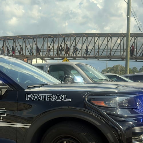 Students leave Warner Robins High School as Houston County Sheriff vehicles remain on the scene after a shooting at the school Wednesday, Aug. 12, 2026, in Warner Robins, Ga. (Joe Kovac/Atlanta Journal-Constitution via AP)