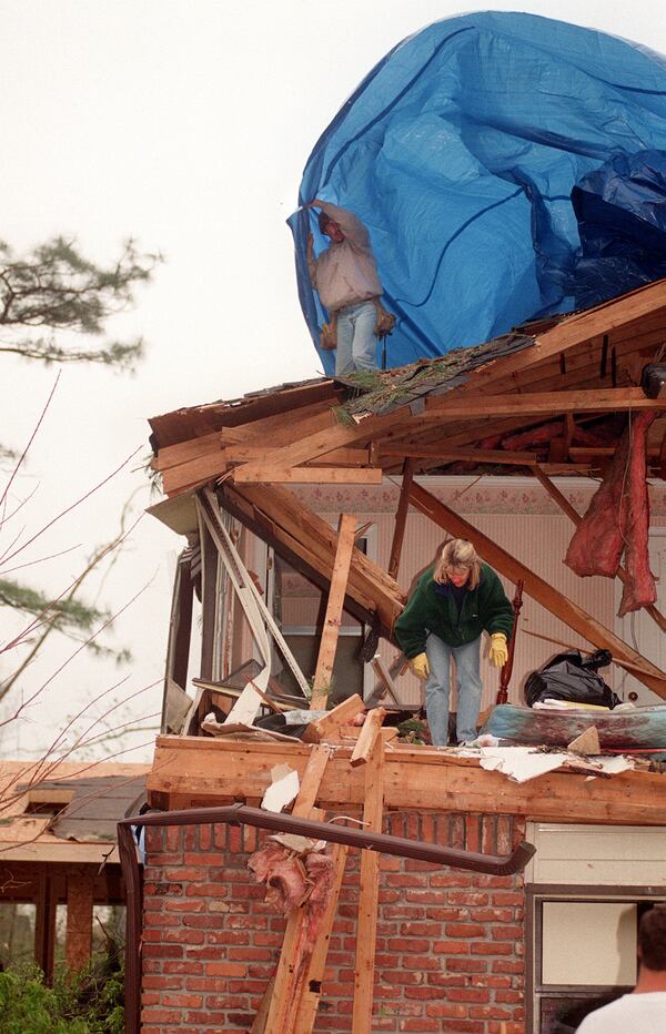 980410 DUNWOODY, GA. Delverton Dr.
Suki Janisch (green) digs through the rubble in the bedroom where her father in law John Janisch was killed Thursday morning when the tornado caused a tree to fall on the home. Greg Nordin (top) with DSI Disaster Services prepares to tarp the roof to keep the rain out. (AJC STAFF/CATHY SEITH)
