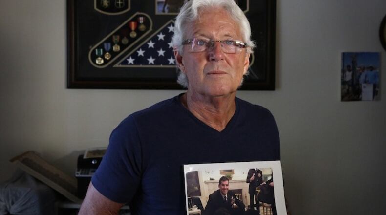 William Owens holds a photo of his youngest son Navy SEAL William "Ryan" Owens in Lauderdale by the Sea, Fla. Ryan Owens was killed during an anti-terrorism raid in Yemen. In the photo Ryan Owens was visiting the White House and posed for a photo with then President Barack Obama's dogs after being awarded medals for his service. (Emily Michot/Miami Herald via AP)