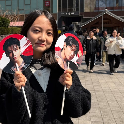 Tian Xin, a BTS fan from Gansu province, China, poses for a photo with handheld fans featuring BTS member Jung Kook, ahead of BTS's comeback concert near Gwanghwamun Square in Seoul, South Korea, Saturday, March 21, 2026. (AP Photo/ Juwon Park)