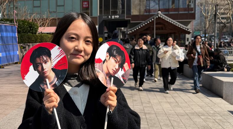 Tian Xin, a BTS fan from Gansu province, China, poses for a photo with handheld fans featuring BTS member Jung Kook, ahead of BTS's comeback concert near Gwanghwamun Square in Seoul, South Korea, Saturday, March 21, 2026. (AP Photo/ Juwon Park)