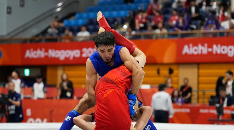 Firdaus Atamuratov of Uzbekistan, bottom, competes with Mirzobek Umarov of Tajikistan during their men's modern 60kg mixed martial arts final at the Asian Games in Nagoya, Japan, Tuesday, Sept. 22, 2026. (AP Photo/Dita Alangkara)