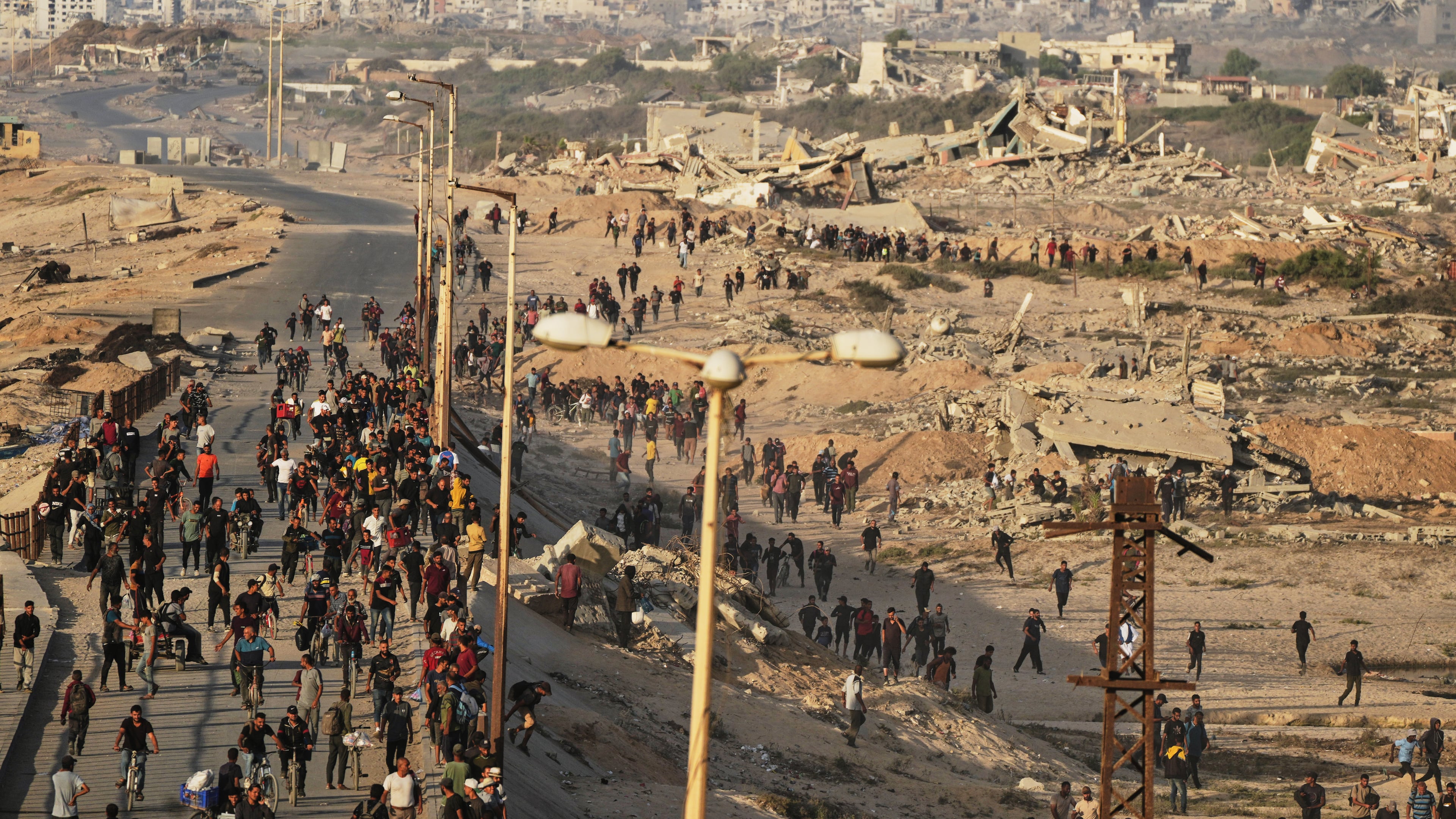 Israeli tanks are positioned on the coastal road leading to Gaza City as displaced Palestinians gather near Wadi Gaza in the central Gaza Strip, Thursday, Oct. 9, 2025. (AP Photo/Abdel Kareem Hana)