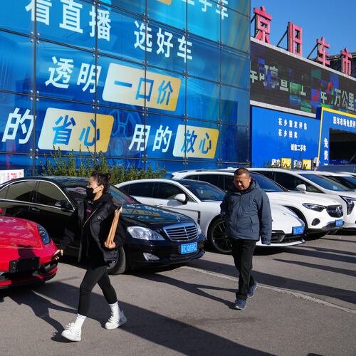 People walk past a second hand market for luxury cars in Beijing, Tuesday, Nov. 25, 2025. (AP Photo/Andy Wong)