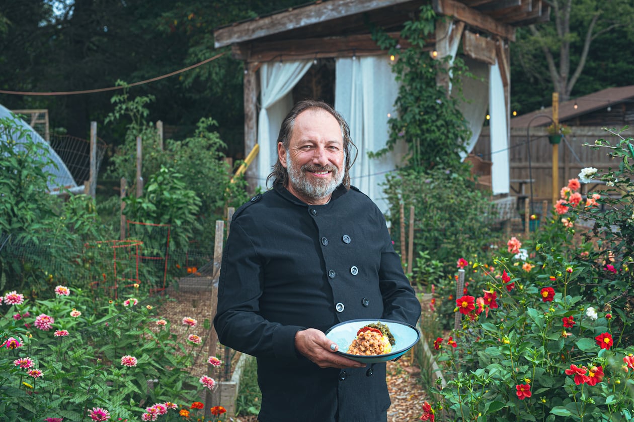 Executive chef and owner Mark Henegan of the Bush Farmhouse poses in the restaurant's garden with a bowl of his South African-inspired hoppin' John. (Grace Dickinson for The Atlanta Journal-Constitution)