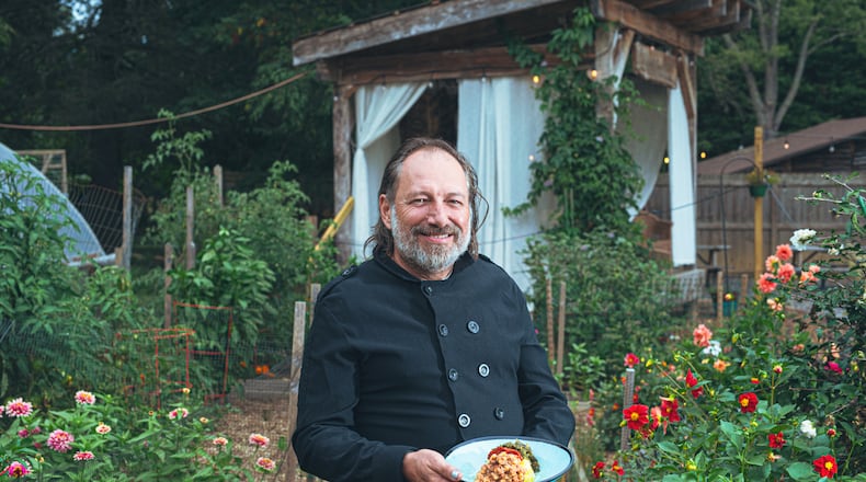 Executive chef and owner Mark Henegan of the Bush Farmhouse poses in the restaurant's garden with a bowl of his South African-inspired hoppin' John. (Grace Dickinson for The Atlanta Journal-Constitution)