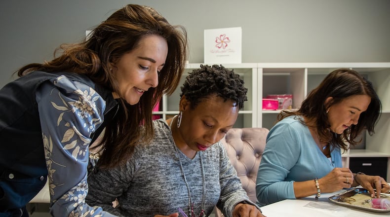 Atlanta artist, Biviana Franco (from left) helps Amanda Hopkins and Sharondalyn Newton created artwork & jewelry at the Feel Beautiful Today studio in Roswell. Bivi created Feel Beautiful Today to help cancer patients by going to hospitals and helping them make jewelry and do other projects aimed at making them feel beautiful during a touch time. Photo by Phil Skinner