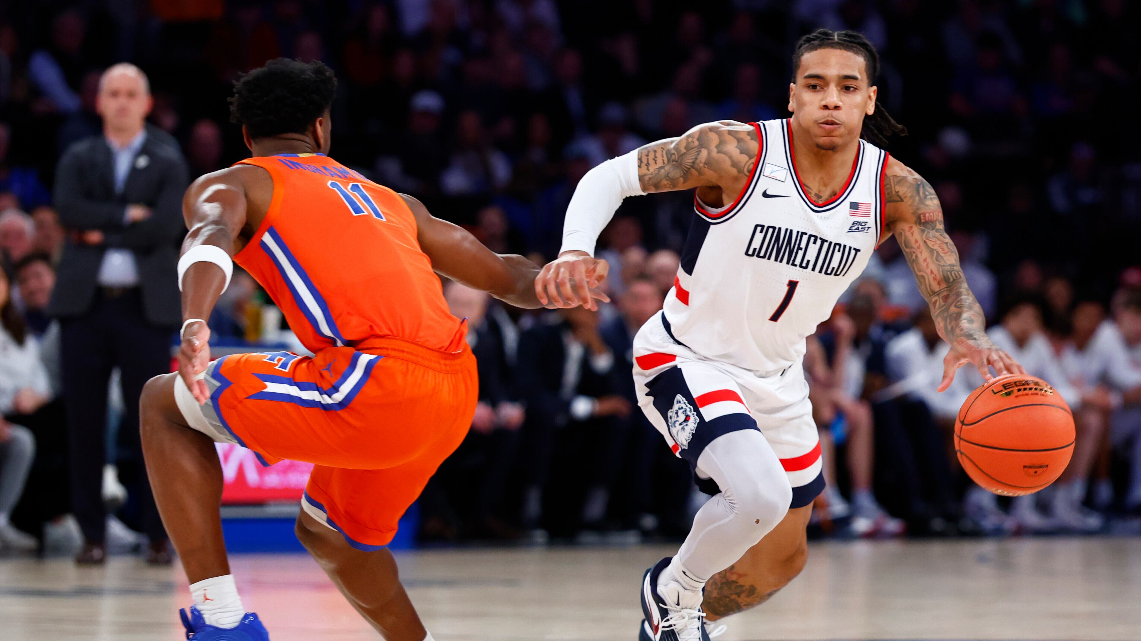 UConn guard Solo Ball (1) drives to the basket against Florida guard CJ Ingram II (11) during the first half of an NCAA basketball game, Tuesday, Dec. 9, 2025, in New York. (AP Photo/Noah K. Murray)