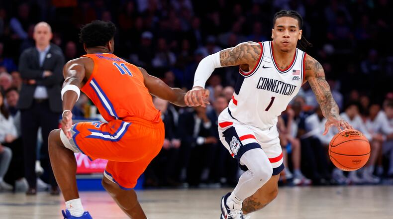 UConn guard Solo Ball (1) drives to the basket against Florida guard CJ Ingram II (11) during the first half of an NCAA basketball game, Tuesday, Dec. 9, 2025, in New York. (AP Photo/Noah K. Murray)